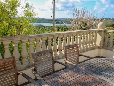 An outdoor patio with wooden table and chairs overlooking a river and countryside at Hindon Hall in Lelant near Carbis Bay