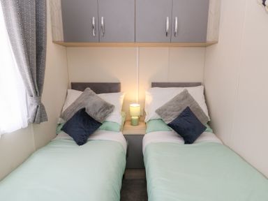 A bedroom with two single beds and a lamp on a shared bedside table at The Haven