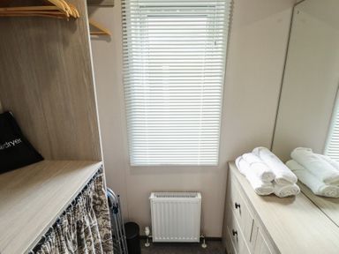 A bedroom with a wardrobe and towels at Heather William Lodge near Woodhall Spa