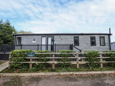 An exterior view of a lodge with a deck and steps at Heather William Lodge near Woodhall Spa