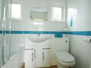 A bathroom with a sink cabinet towels toilet and bathtub at The Beach Hut in Cromer