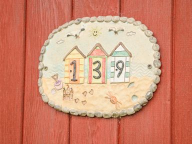 A house number plaque on a red wooden door with beach huts and the number 139 at The Beach Hut in Cromer