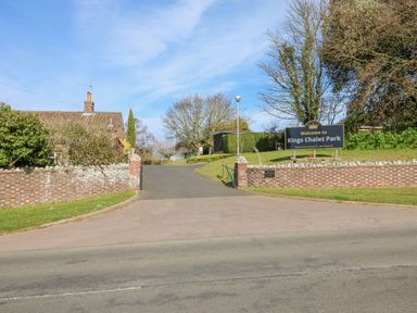 Entrance road to Kings Chalet Park with brick walls and a welcome sign