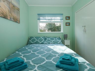 A bedroom with a bed covered with patterned bedding and folded towels on top at The Beach Hut in Cromer