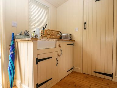 A kitchen corner with a sink toaster dish rack and an umbrella at Mitford Gypsy Hut in Moreton-In-Marsh
