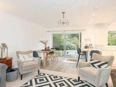 A living area with two armchairs and a dining table with chairs near sliding glass doors at 15 Maes Awel in Abersoch