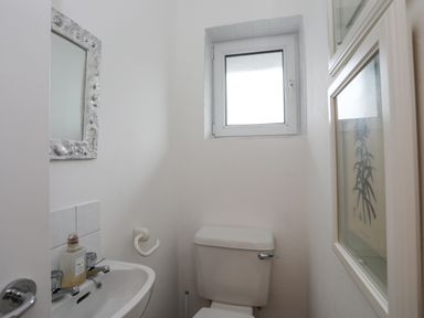 A small bathroom with a toilet sink mirror and framed pictures at 15 Maes Awel in Abersoch