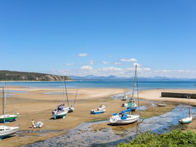 Sailboats and small boats on a sandy beach with the sea and mountains in the background at 15 Maes Awel in Abersoch