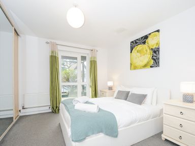 A bedroom with a double bed bedside tables lamps and a floral painting at 24 Valley Lodge in Honicombe Park near Drakewalls