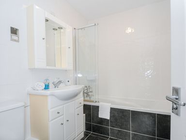 A bathroom with a sink cabinet mirror toilet and bathtub with a glass shower screen at 24 Valley Lodge in Honicombe Park near Drakewalls