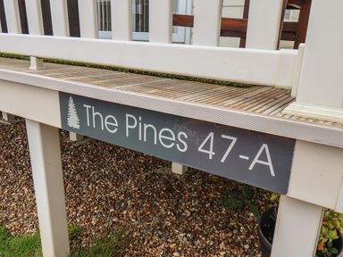 A porch with a wood deck and a sign reading The Pines 47-A at Evergreen Pines in Cayton Bay near Scarborough