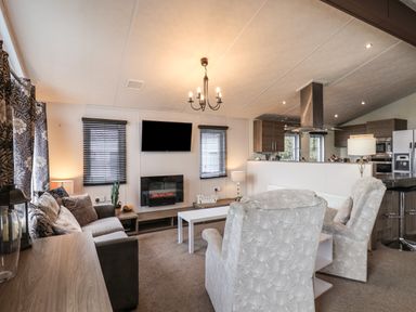 A living room with a sofa armchairs a TV and a fireplace at Evergreen Pines in Cayton Bay near Scarborough