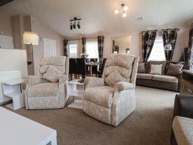 A living room with two armchairs a sofa a dining table and chairs and a floor lamp at Evergreen Pines in Cayton Bay near Scarborough