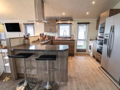 A kitchen with bar stools a gas stove a sink washing machine and refrigerator at Evergreen Pines Cayton Bay near Scarborough