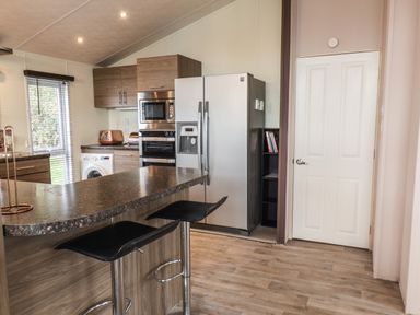 A kitchen with a refrigerator oven microwave washing machine and bar stools at Evergreen Pines in Cayton Bay near Scarborough