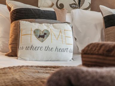 Close up of decorative cushions on a bed with a cushion saying home is where the heart is at Evergreen Pines in Cayton Bay near Scarborough
