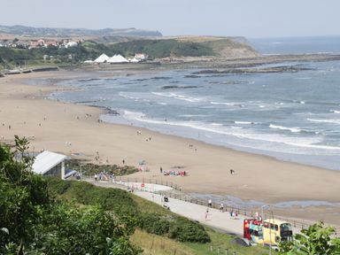 A beach scene with people and a bus at Evergreen Pines Cayton Bay near Scarborough