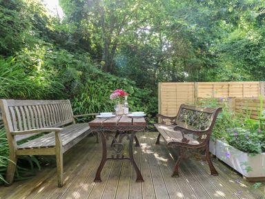 A garden with a wooden table and benches at Oofoo’s Barn in Mullion