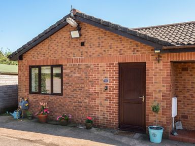 A brick exterior of a property with a door and window at Piglet Corner in Culmstock