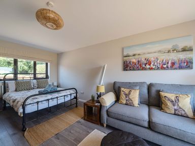 A bedroom with a bed and a sofa at Piglet Corner in Culmstock