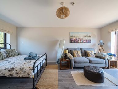A bedroom with a bed and sofa at Piglet Corner in Culmstock