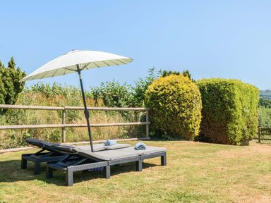 A garden with lounge chairs and an umbrella at Piglet Corner in Culmstock