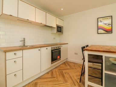 A kitchen with white cabinets wooden countertop and dining table with chairs at Valise in Bideford