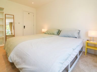 A bedroom with two beds with pillows a yellow nightstand with a lamp a mirror and a door at Valise in Bideford