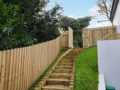 A wooden staircase going uphill between a wooden fence and a grassy slope at Valise in Bideford