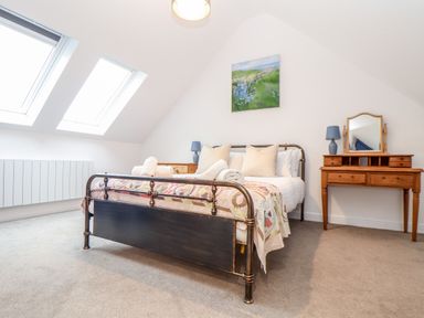 A bedroom with a metal bed frame with pillows and towels and a wooden dressing table with a mirror at Wildwood in Newquay