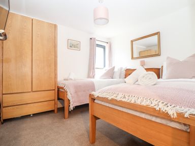 A bedroom with two single beds wooden wardrobe window and mirror at Wildwood in Newquay