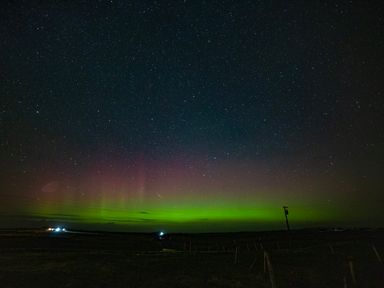 A night sky with stars and aurora borealis over a rural landscape at Heisgeir Sollas Isle Of North Uist