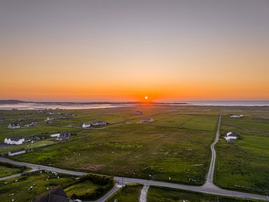 A rural landscape with fields houses and roads at sunset at Heisgeir Sollas Isle Of North Uist