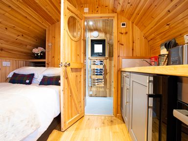 A wooden bedroom with a bed and a kitchenette at Heisgeir in Sollas Isle Of North Uist
