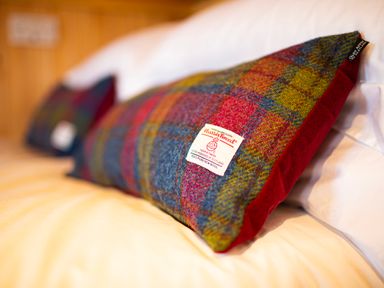 A close up of a Harris Tweed cushion on a white bed at Heisgeir Sollas Isle Of North Uist