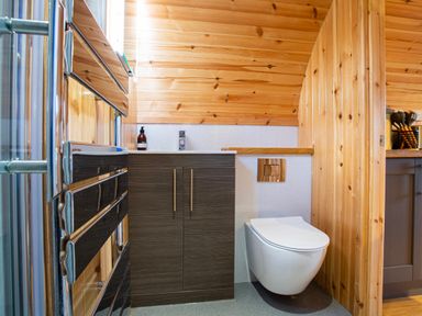 A bathroom with a wall-mounted toilet and cabinet under a sink at Heisgeir Sollas Isle Of North Uist