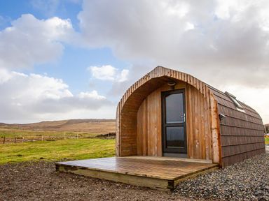A small wooden cabin with a black door and a deck in a rural landscape at Heisgeir in Sollas Isle Of North Uist