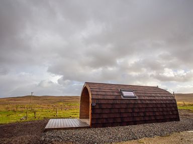 A small wooden cabin with a curved roof and a skylight in a grassy open field at Heisgeir in Sollas Isle Of North Uist