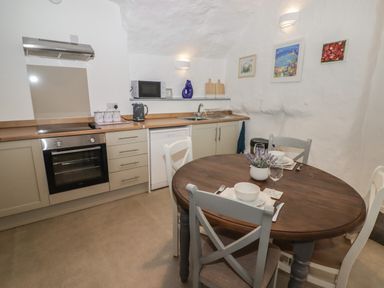 A kitchen with oven stovetop dishwasher and a round dining table with four chairs at Le Durkestrete Cellar in Haverfordwest