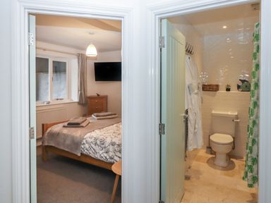 A bedroom with a bed and towels next to a bathroom with a toilet and bathrobe at Le Durkestrete Cellar in Haverfordwest
