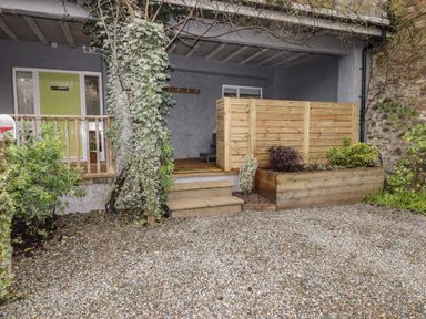 An outdoor patio area with a wooden fence and planter boxes with plants at Le Durkestrete Cellar in Haverfordwest