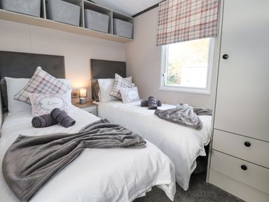 A bedroom with two single beds and a window with plaid blinds at Ginger Fox Lodge East Heslerton near Cayton