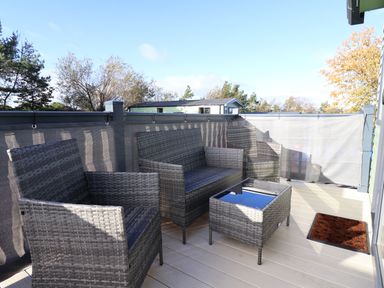 An outdoor patio with woven furniture including two armchairs a loveseat and a glass top table at Ginger Fox Lodge in East Heslerton near Cayton