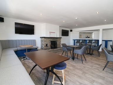 A lounge area with tables chairs a stone fireplace and two wall-mounted televisions at Ginger Fox Lodge in East Heslerton near Cayton