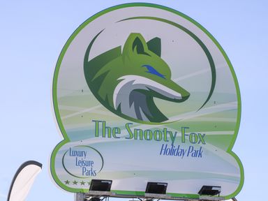 A signboard with a green fox logo and text The Snooty Fox Holiday Park Luxury Leisure Parks