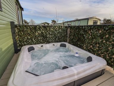 An outdoor hot tub with bubbling water surrounded by privacy screens with leaf patterns at Ginger Fox Lodge in East Heslerton near Cayton
