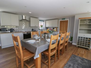 A kitchen with a dining table set for eight with wooden chairs at Curtau in Llanfaredd near Builth Wells