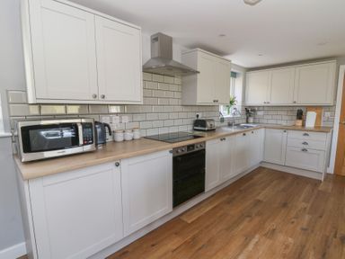 A kitchen with white cabinets wooden countertops microwave kettle and toaster at Curtau Llanfaredd near Builth Wells