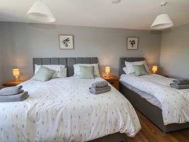 A bedroom with two beds with white bedding and green pillows at Curtau in Llanfaredd near Builth Wells