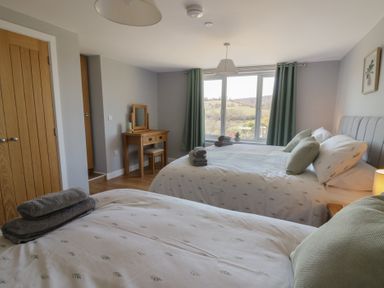 A bedroom with two beds a wooden dressing table and green curtains at Curtau Llanfaredd near Builth Wells